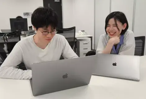 2名のエンジニアが楽しそうにPC作業をしている様子
